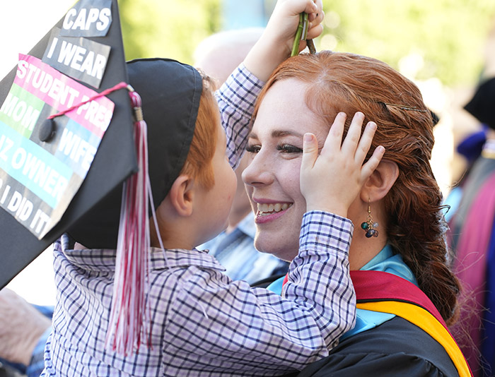 red haired woman holding son with graduation cap on